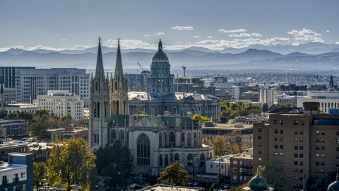 DXP001_000171 - Aerial stock photo of A cathedral and Colorado State Capitol dome with mountains in the background, Downtown Denver, Colorado