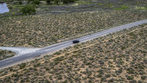 DXP001_007_0002 - Aerial stock photo of A black SUV parked on a desert road in Carson City, Nevada