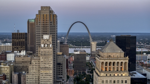 A view of the Gateway Arch between a skyscraper and a courthouse at twilight, Downtown St. Louis, Missouri Aerial Stock Photos | DXP001_036_0011