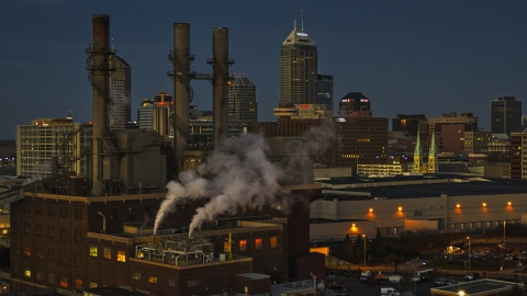 Factory smoke stacks with view of the city skyline at twilight, Downtown Indianapolis, Indiana Aerial Stock Photos | DXP001_093_0003