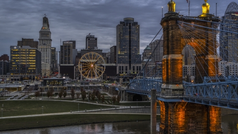 DXP001_097_0014 - Aerial stock photo of The Roebling Bridge near the Ferris wheel and city skyline at sunset, Downtown Cincinnati, Ohio