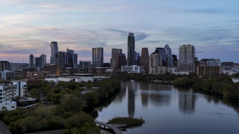 DXP002_110_0011 - Aerial stock photo of The city's waterfront skyline seen from low over Lady Bird Lake at twilight in Downtown Austin, Texas