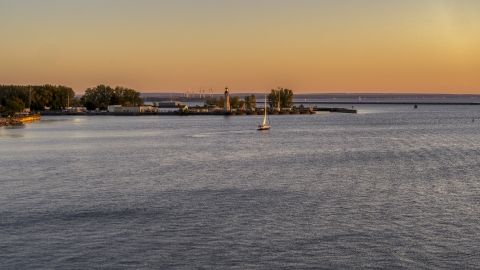 DXP002_204_0007 - Aerial stock photo of A sailboat on Lake Erie near lighthouse at sunset, Buffalo, New York