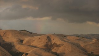 8K aerial stock footage of a rainbow behind brown mountains at sunset in Northern California Aerial Stock Footage | AF0001_001033