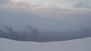 AK0001_0071 - 4K aerial stock footage flying over snowy peak, revealing Eklutna Lake, Alaska