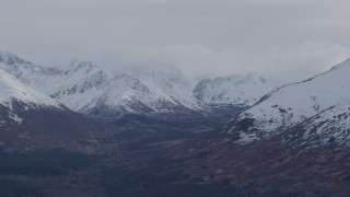 4K aerial stock footage flying by a valley, snow capped, cloud covered Chugach Mountains, Alaska Aerial Stock Footage | AK0001_0255