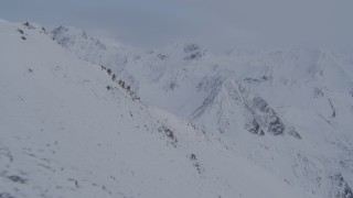 4K aerial stock footage flying by snowy slope, revealing Chugach Mountains, Alaska Aerial Stock Footage | AK0001_0261