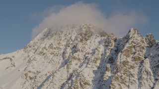 4K aerial stock footage flying by snow covered peak, capped with clouds, Chugach Mountains, Alaska Aerial Stock Footage | AK0001_0294