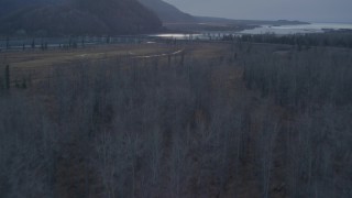 AK0001_0313 - 4K aerial stock footage flying over the forest, revealing two bridges spanning the Knik River, Alaska, twilight