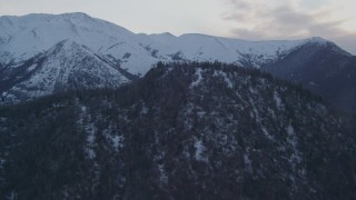 4K aerial stock footage fly over wooded summit, approaching snowy Chugach Mountains, Alaska, twilight Aerial Stock Footage | AK0001_0319