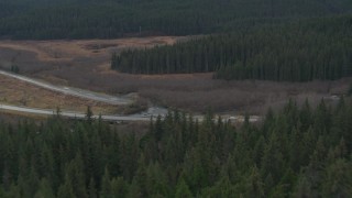 4K aerial stock footage flying low over trees, revealing Seward Highway spanning river, Portage, Alaska Aerial Stock Footage | AK0001_0378