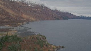 AK0001_0484 - 4K aerial stock footage follow shoreline, approaching snow capped peaks, Blackstone Bay, Alaska