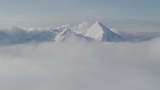 4K aerial stock footage flying by snow covered Kenai Mountains, low clouds, Kenai Mountains, Alaska Aerial Stock Footage | AK0001_0535