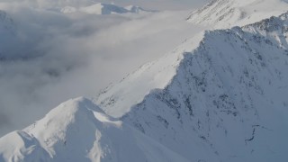 4K aerial stock footage descending a snowy ridge, approaching low clouds, Kenai Mountains, Alaska Aerial Stock Footage | AK0001_0541