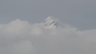 4K aerial stock footage flying by snow covered peak, low clouds, Chugach Mountains, Alaska Aerial Stock Footage | AK0001_0553