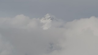 4K aerial stock footage flying by snowy summit surrounded by low clouds, Chugach Mountains, Alaska Aerial Stock Footage | AK0001_0554