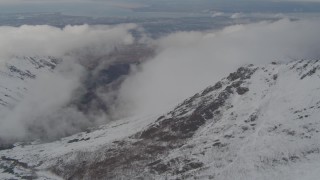 4K aerial stock footage flying by snow capped mountains, with low clouds, Chugach Mountains, Alaska Aerial Stock Footage | AK0001_0570