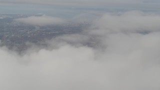 4K aerial stock footage tilt up from thick clouds, revealing Downtown Anchorage, Alaska Aerial Stock Footage | AK0001_0578