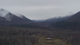 4K aerial stock footage flying by wooded valley, houses, snow-capped Chugach Mountains, Alaska Aerial Stock Footage | AK0001_0624