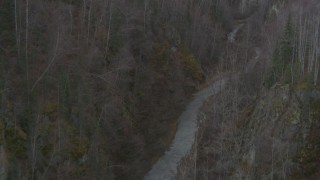 AK0001_0630 - 4K aerial stock footage tilting down over a river at bottom of gorge, tilt up to forest, Birchwood, Alaska