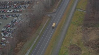 AK0001_0659 - 4K aerial stock footage tracking school bus, Old Glenn Highway, past junkyard, Chugiak, Alaska