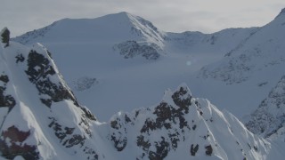 4K aerial stock footage flying over snow-covered rocky ridge, pan across Chugach Mountains, Alaska Aerial Stock Footage | AK0001_0827