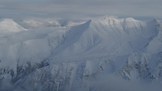 AK0001_0835 - 4K aerial stock footage panning across clouds, snow-covered Chugach Mountains, Alaska