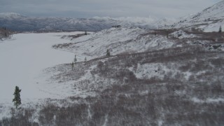 AK0001_0889 - 4K aerial stock footage fly over snow covered Alaskan Wilderness toward center of Goober Lake, Alaska