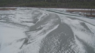 AK0001_0896 - 4K aerial stock footage flying over tree lined, snowy bank of river, during winter Tazlina River Valley, Alaska