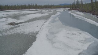 AK0001_0897 - 4K aerial stock footage flying low over the icy, snow covered river during winter in the Tazlina River Valley, Alaska