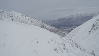 4K aerial stock footage flying over snowy slope, reveal valley, Chugach Mountains, Alaska Aerial Stock Footage | AK0001_0952