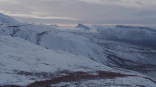 AK0001_1060 - 4K aerial stock footage flying over snowy slopes and jagged peaks in the Talkeetna Mountains, Alaska