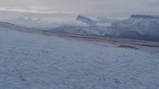 AK0001_1061 - 4K aerial stock footage flying over a snowy slope toward Talkeetna Mountains, Alaska