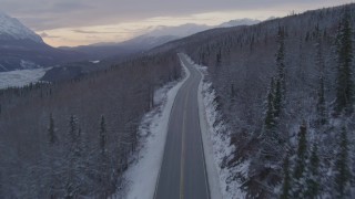 4K aerial stock footage following Glenn Highway and snow covered forest near Sutton at twilight, Alaska Aerial Stock Footage | AK0001_1101