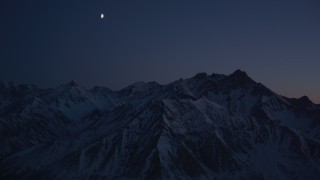 4K aerial stock footage the moon over the snow covered Chugach Mountains at night, Alaska Aerial Stock Footage | AK0001_1133