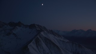 4K aerial stock footage the moon above the snow covered Chugach Mountains at night, Alaska Aerial Stock Footage | AK0001_1138