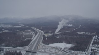 4K aerial stock footage following Glenn Highway toward power plant in snow, Anchorage, Alaska Aerial Stock Footage | AK0001_1151