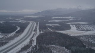 4K aerial stock footage flying beside snow covered Glenn Highway, Fort Richardson, Anchorage, Alaska Aerial Stock Footage | AK0001_1155