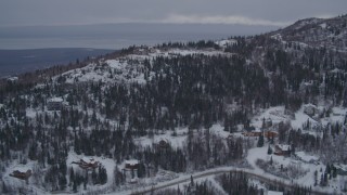 4K aerial stock footage flying over snow covered, wooded hills and homes in Eagle River, Alaska Aerial Stock Footage | AK0001_1165