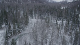 4K aerial stock footage flying over snowy, wooded valley revealing a river, Chugach Mountains, Alaska Aerial Stock Footage | AK0001_1196