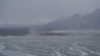 4K aerial stock footage Knik River Valley with snow flurried by wooded shoreline, Alaska Aerial Stock Footage | AK0001_1217