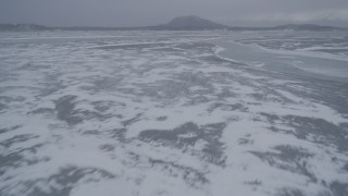 AK0001_1262 - 4K aerial stock footage flying over frozen ground and rivers with ice sheets, Knik River Valley, Alaska