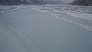 AK0001_1275 - 4K aerial stock footage following an icy river over frozen banks, Butte, Alaska