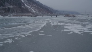 AK0001_1277 - 4K aerial stock footage flying over frozen ground toward Old Glenn Highway bridge, Butte, Alaska in snow