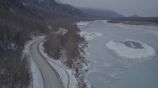 AK0001_1279 - 4K aerial stock footage flying between Old Glenn Highway and icy river over snow, Butte, Alaska