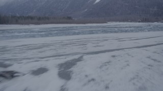 AK0001_1296 - 4K aerial stock footage flying over a snowy riverbank and icy river, Knik River Valley, Alaska