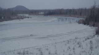 4K aerial stock footage ascending over trees, snowy riverbank, icy river, Knik River Valley, Alaska Aerial Stock Footage | AK0001_1298