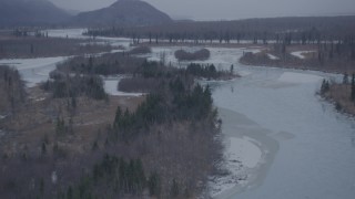 4K aerial stock footage flying over snow covered forest and icy river, Knik River Valley, Alaska Aerial Stock Footage | AK0001_1299