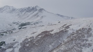 4K aerial stock footage flying up a snow covered slope revealing peaks in the Chugach Mountains, Alaska Aerial Stock Footage | AK0001_1336