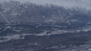 AK0001_1345 - 4K aerial stock footage flying over snowy slope revealing a rocky range in the Chugach Mountains, Alaska